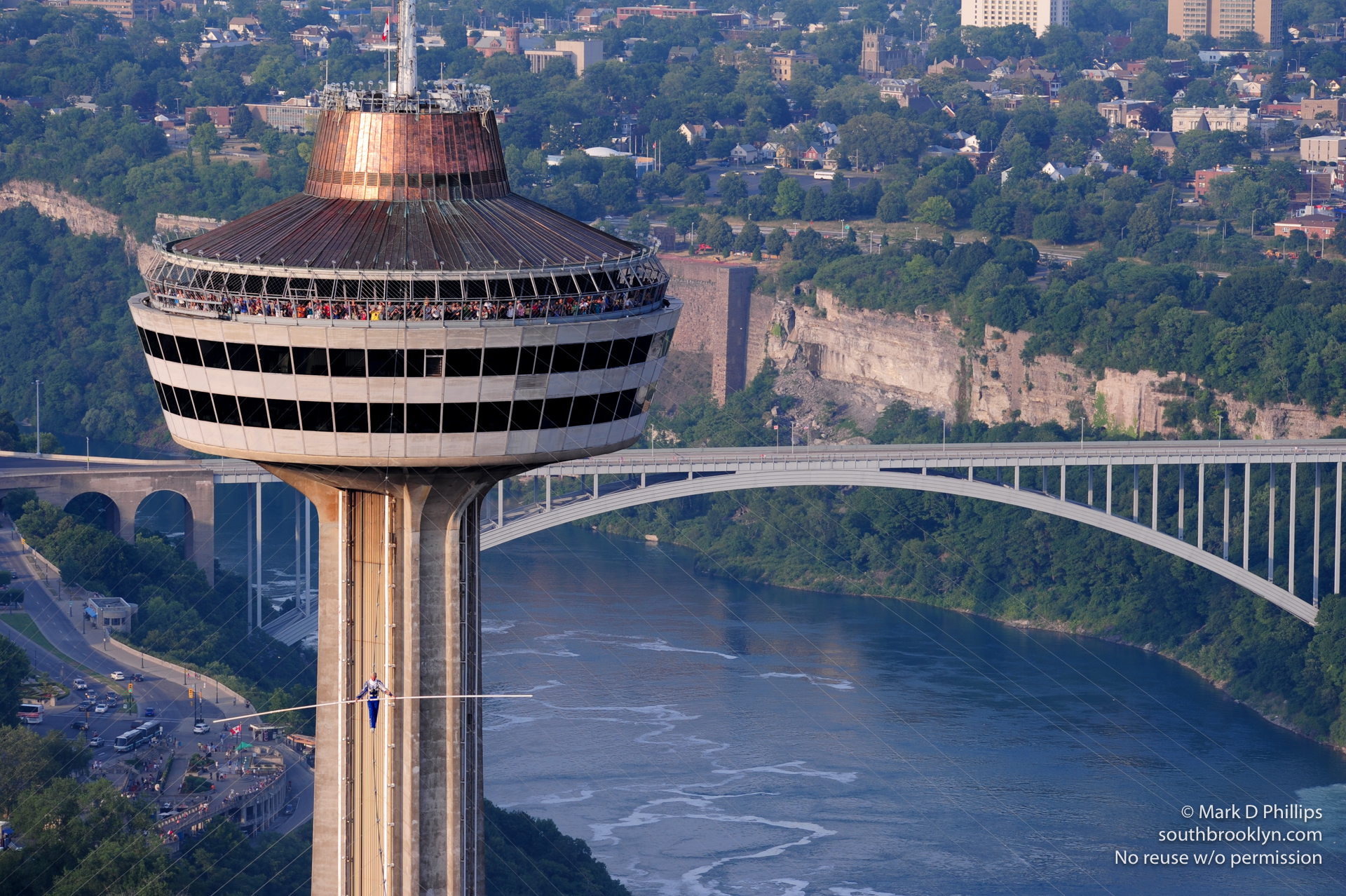 High above Niagara Gorge and the Rainbow Bridge, Jay Cochrane walks from the Skylon Tower on his Highway in the Sky on July 6, 2012. ©Mark D Phillips